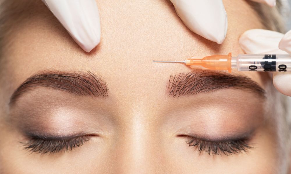A woman receiving Botox treatment via injection above her left eyebrow