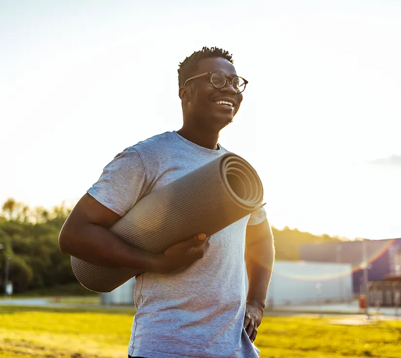 Young man outside with yoga mat