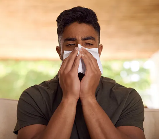 Young man blowing nose, constant congestion