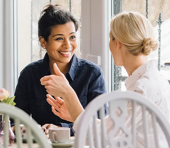 Woman wearing hearing aid talking to friend